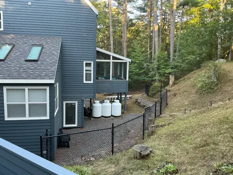 Chain-link fence around a sloped yard near a blue house