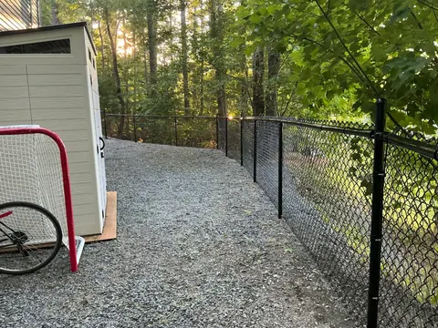 Chain-link fence curving through a wooded yard