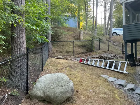 In-progress chain-link fence installation around large rocks